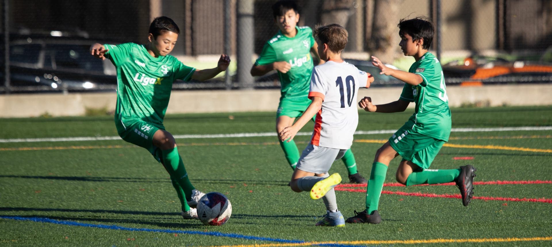 Young players competing for the ball on a sunlit pitch